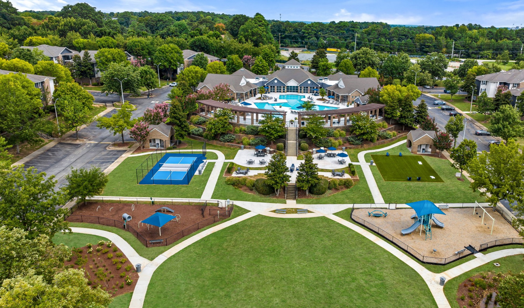 Drone view of outdoor amenity space with playground, pet park, pickleball, grills and seating 