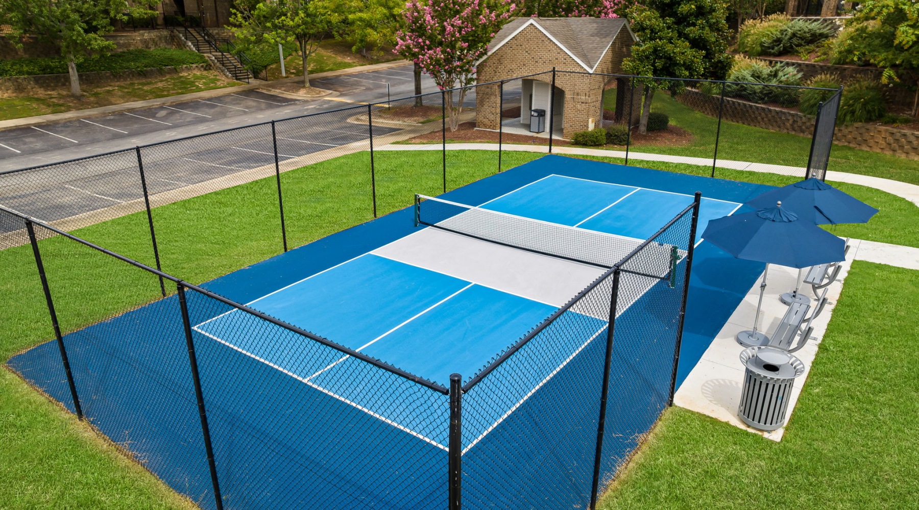 A blue pickleball court with bench seating and umbrellas at 403 West apartments in Raleigh, NC.